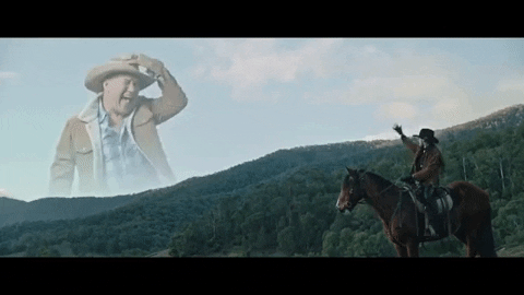 gif of cowboy looking at cowboy god who is singing
